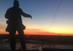 Professional roofer inspecting storm damage on a metal roofing system in Milano, Texas.