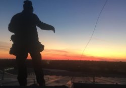 Professional roofer inspecting storm damage on a metal roofing system in Milano, Texas.