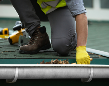 Cleaning gutters as part of roof maintenance in Hutto
